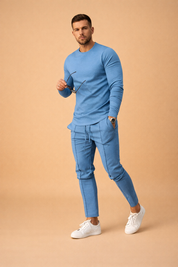 Light blue fitted long-sleeve crewneck shirt paired with matching slim-fit drawstring trousers and white low-top sneakers in a clean coordinated menswear set