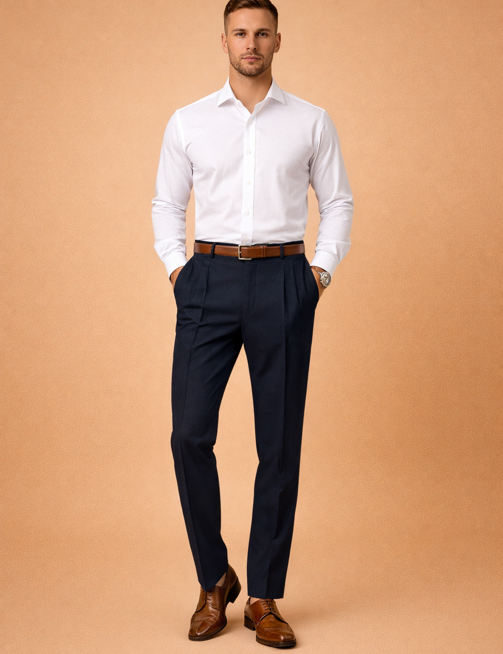 Men’s tailored navy dress trousers with clean front pleats and slim straight-leg cut, styled with a crisp white long-sleeve shirt, brown leather belt, and polished brown lace-up dress shoes