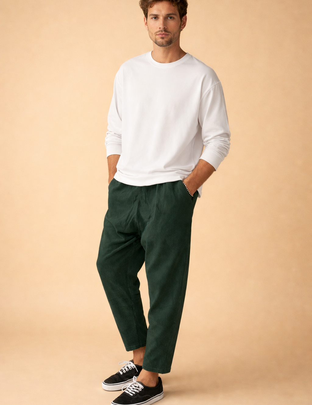 Tailored men’s trousers with a clean tapered leg, subtle textured fabric, elasticated waistband, and ankle-length cut, styled with a minimalist long-sleeve top and low-profile lace-up sneakers for a modern casual look.