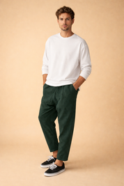 Tailored men’s trousers with a clean tapered leg, subtle textured fabric, elasticated waistband, and ankle-length cut, styled with a minimalist long-sleeve top and low-profile lace-up sneakers for a modern casual look.