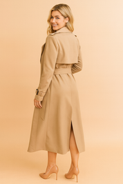 Beige trench coat with belted waist, epaulets, back storm flap, and cuff straps, styled with nude pumps