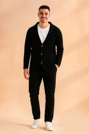 Black two-button blazer-style cardigan with front patch pockets, styled over a white T-shirt, slim black trousers, and white sneakers for a modern casual look.