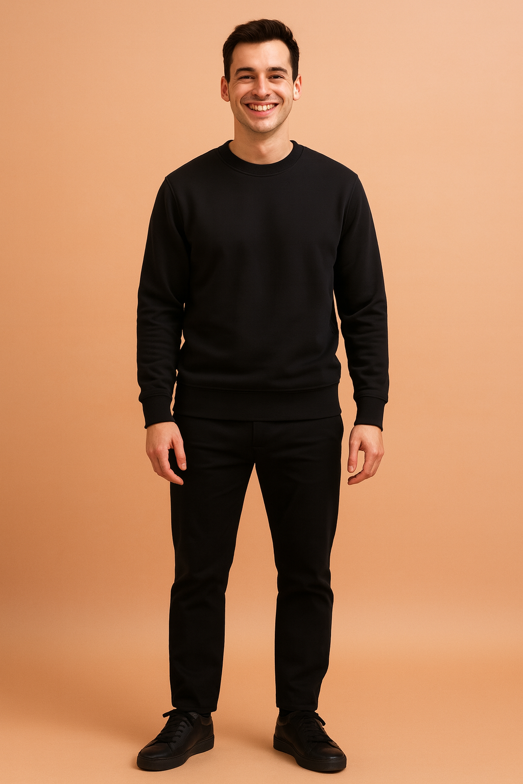 Men's classic black crewneck sweatshirt with long sleeves and ribbed cuffs, styled with straight black trousers and matching black sneakers for a clean, modern casual outfit.