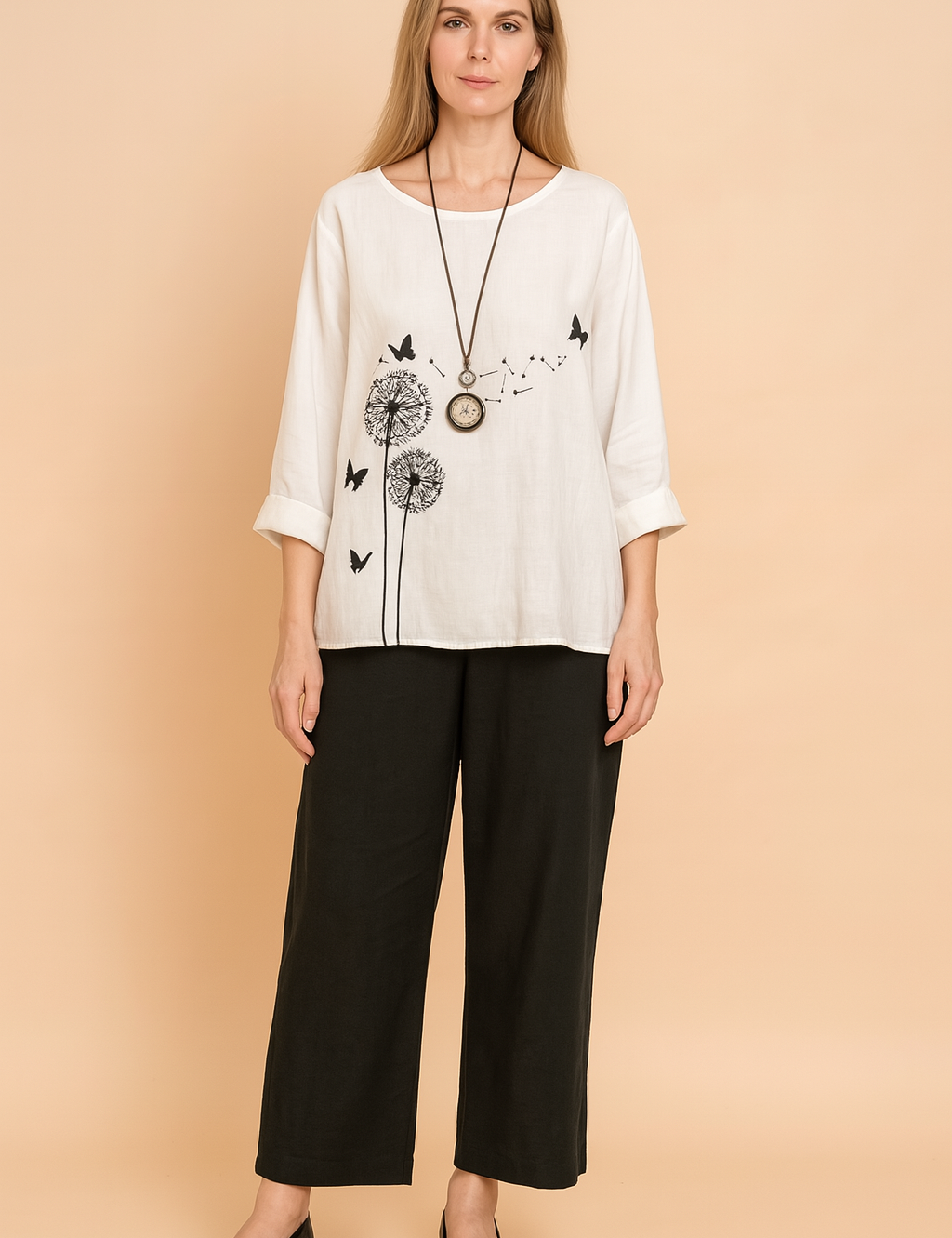 White linen three-quarter sleeve blouse with black dandelion and butterfly print, paired with black straight-leg ankle-length pants made of soft, flowy fabric.