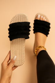 Beige woven slide sandals with triple-layered black fringed fabric straps and flat soles