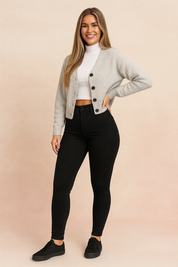 High-waisted black jeggings paired with a cropped white turtleneck and a button-up cardigan, styled with black sneakers for a sleek and casual look
