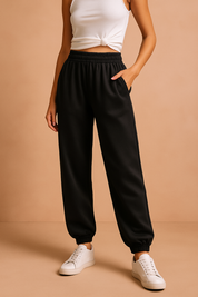 Black high-waisted jogger sweatpants with an elastic waistband and ankle cuffs, styled with white sneakers for a casual streetwear look.