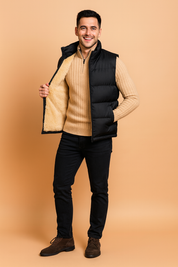 Black padded sleeveless winter vest with beige fleece lining, designed for warmth and comfort, styled with front zipper closure and side pockets.
