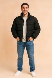 Black puffer jacket with quilted padding, front zip closure, and a high collar, styled casually with a sweatshirt and jeans for a modern winter look.