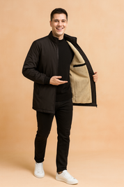 Black bomber jacket with beige faux-shearling lining, zip-up front, ribbed cuffs and hem, styled with slim black pants for a modern winter look.