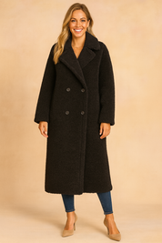 Long black teddy-texture double-breasted coat with wide lapels, paired with fitted jeans and beige heels.