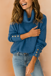 Blue ribbed knit cowl-neck sweater with decorative gold-tone buttons on the sleeves, styled with mid-rise blue denim jeans.