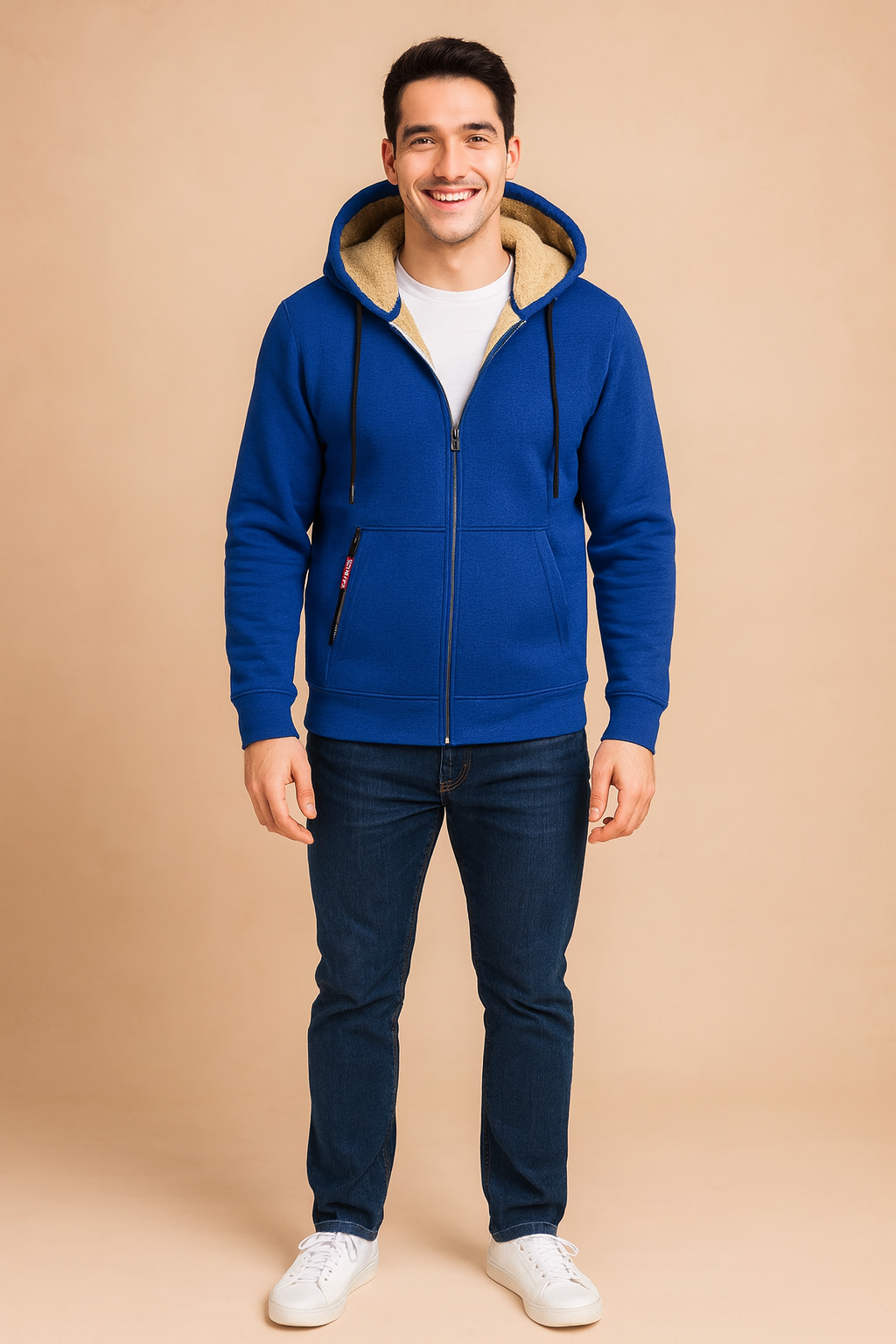 Blue fleece-lined zip-up hoodie jacket with beige faux fur interior, black drawstrings, and zippered pockets, styled with casual jeans and white sneakers.