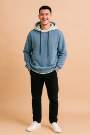 Casual men’s hoodie in soft blue with contrasting light gray hood lining and black drawstrings, styled with ribbed cuffs, hem, and a front patch detail for a modern streetwear look.