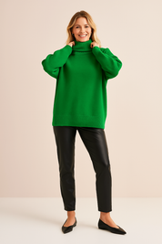 Vibrant green oversized turtleneck sweater with ribbed hem, cuffs, and collar, paired with sleek black faux leather pants and pointed black flats