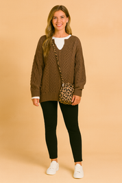 Oversized sweater with classic cable pattern, paired with a white inner shirt, slim black pants, white sneakers, and a leopard-print shoulder bag