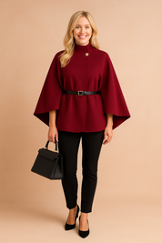 Burgundy cape jacket with belted waist and button detail, styled with black trousers and handbag for a chic modern look.
