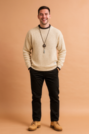 Cream-colored cable-knit pullover sweater featuring ribbed cuffs, hem, and neckline, styled with contrast trim and a hanging pendant necklace—perfect for casual winter fashion.