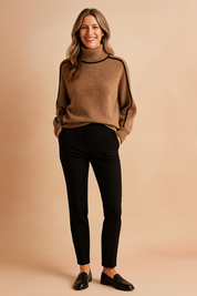 Camel high-neck wool sweater with black piping along the shoulders and sleeves, paired with slim-fit black trousers and classic black loafers.