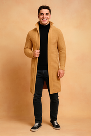 Camel-colored long knit cardigan with ribbed pattern, styled over a black turtleneck and dark jeans, paired with casual black sneakers.