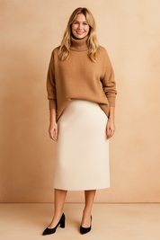 Camel brown oversized turtleneck sweater with ribbed hem and cuffs, paired with a cream midi skirt and black block-heeled shoes