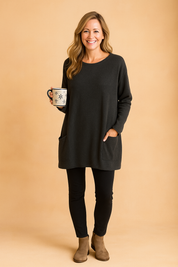 Charcoal gray oversized tunic top with clean front panel and patch pockets, styled with black leggings and taupe ankle boots.
