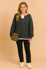 Oversized sweater with classic cable pattern, paired with a white inner shirt, slim black pants, white sneakers, and a leopard-print shoulder bag