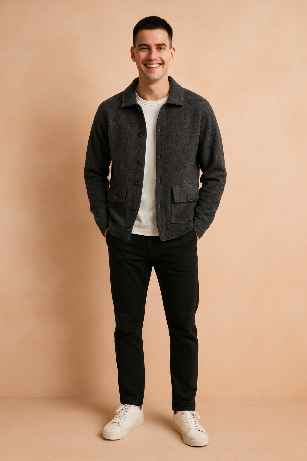 Dark gray wool cardigan with button-up front and flap pockets, styled over a white T-shirt with slim black trousers and white sneakers for a modern casual look.