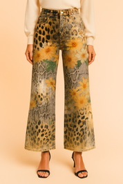 High-waisted wide-leg jeans with a bold mixed print of leopard spots, python snakeskin, and large yellow floral motifs, styled with a cream top and black sandals for a standout fashion look.