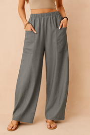 Gray wide-leg linen pants with front patch pockets and a relaxed fit, styled with tan open-toe sandals.