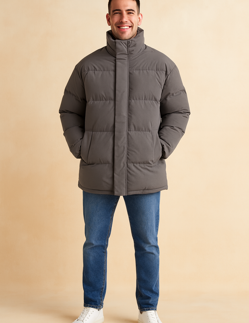 Gray puffer jacket with high collar, hidden front zipper, and side pockets, styled casually with jeans and white sneakers for a modern winter look.