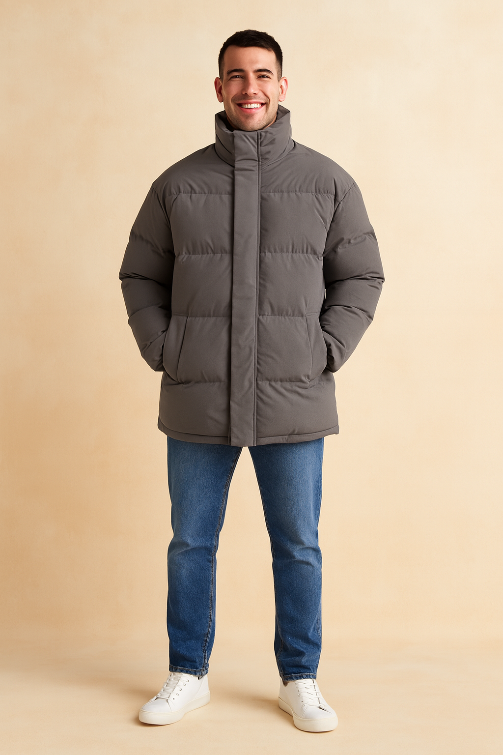 Gray puffer jacket with high collar, hidden front zipper, and side pockets, styled casually with jeans and white sneakers for a modern winter look.