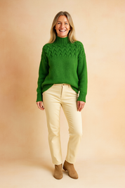 reen cable-knit high-neck sweater paired with cream straight-leg pants and tan suede ankle boots