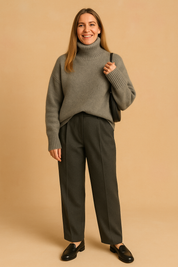 Heather grey ribbed turtleneck sweater in mohair wool, paired with dark charcoal pleated trousers and black leather loafers, styled for a soft autumn studio look.