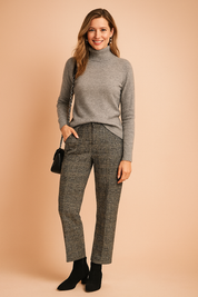 Heather grey fitted knit turtleneck sweater with ribbed collar and cuffs, paired with high-waisted plaid trousers, black suede ankle boots, and a black chain-strap shoulder bag.