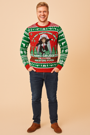 Red and green Christmas sweater featuring Hans Gruber falling from Nakatomi Plaza with festive holiday patterns including snowflakes, dollar signs, guns, and Christmas trees.