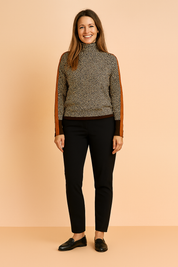 Brown and cream herringbone patterned high-neck sweater with burnt orange sleeve stripes, brown ribbed cuffs, and a matching brown hem, paired with slim-fit black trousers and black loafers.
