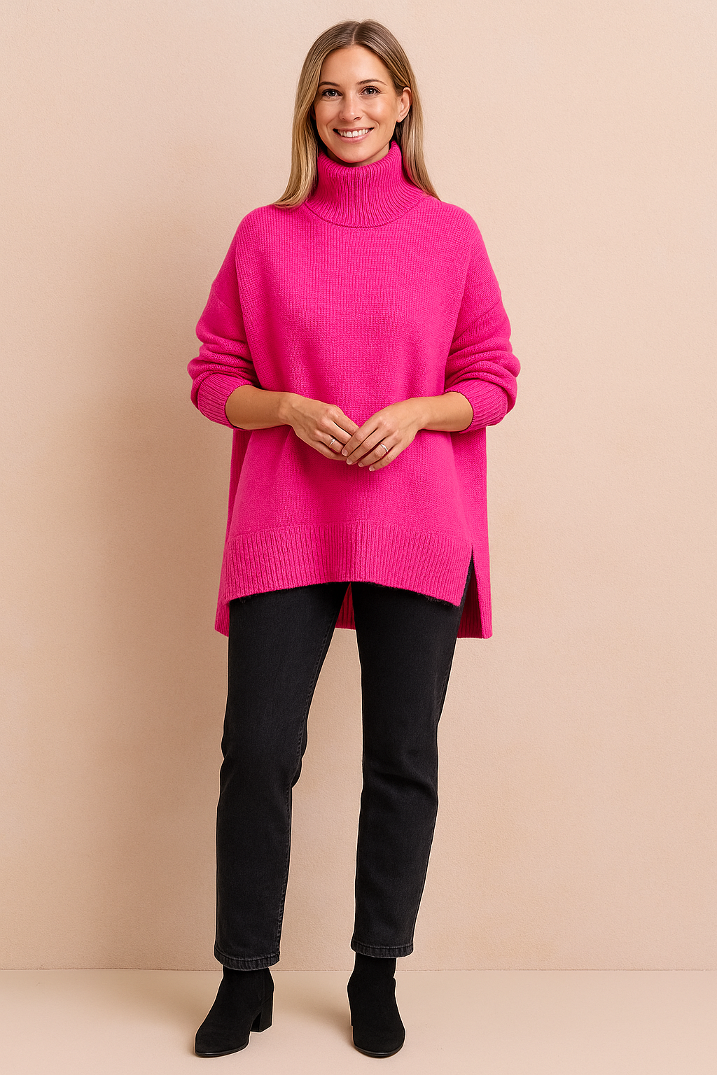 Hot pink oversized knit turtleneck sweater with ribbed hem and high collar, paired with slim-fit black pants and ankle boots.