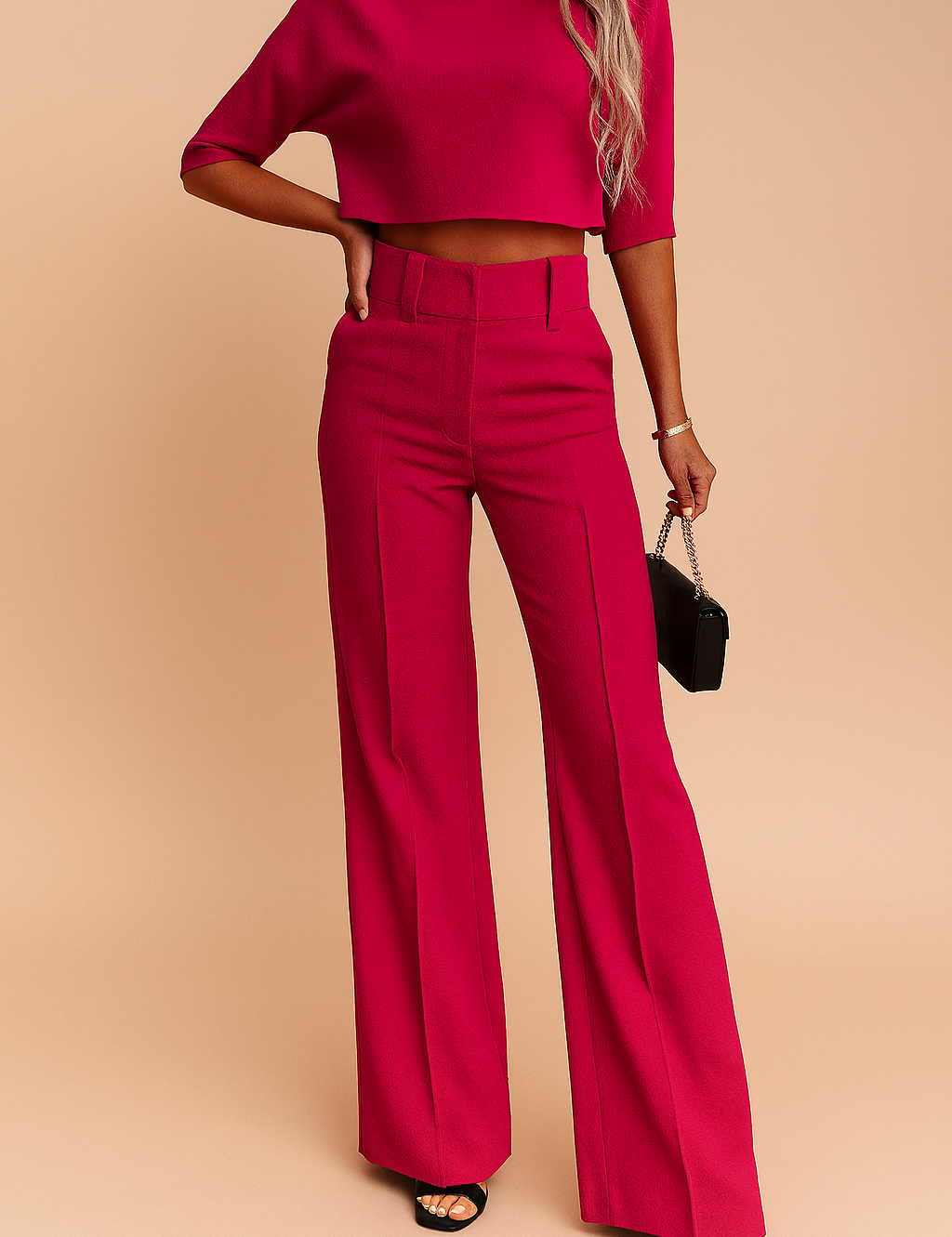 High-waisted hot pink tailored wide-leg trousers with structured seams and belt loops, paired with a matching cropped short-sleeve top made from a textured fabric.