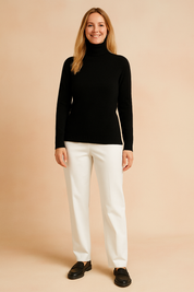 Fitted black knit turtleneck sweater with ribbed collar, hem, and cuffs, styled with crisp white straight-leg trousers and black leather loafers.