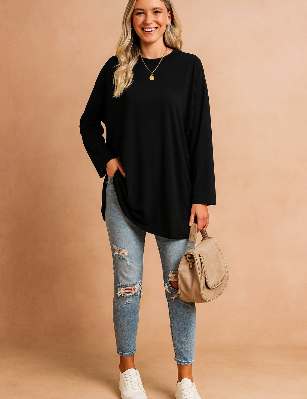 Casual black long-sleeve oversized tunic top paired with light blue distressed skinny jeans, accessorized with a beige shoulder bag and white sneakers.