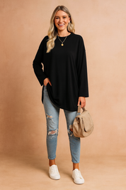 Casual black long-sleeve oversized tunic top paired with light blue distressed skinny jeans, accessorized with a beige shoulder bag and white sneakers.