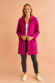 Fuchsia longline button-up jacket with black snap buttons, styled over a white top, paired with dark slim jeans and white sneakers.