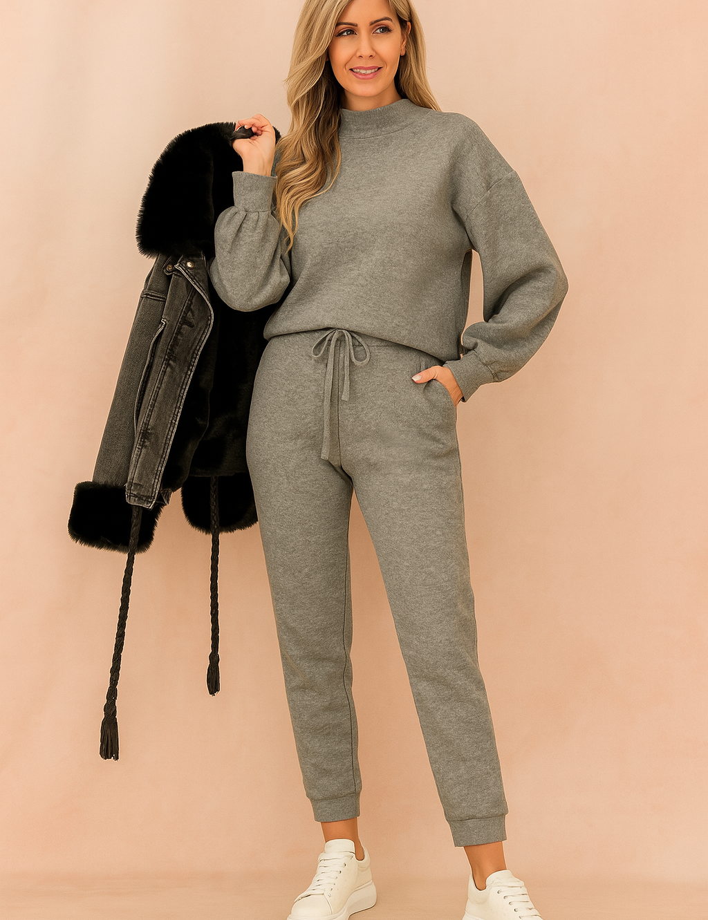 Two-piece heather gray lounge set featuring a relaxed-fit long-sleeve sweatshirt and high-waisted drawstring jogger pants in soft brushed fleece, paired with white sneakers and a black fur-lined denim jacket
