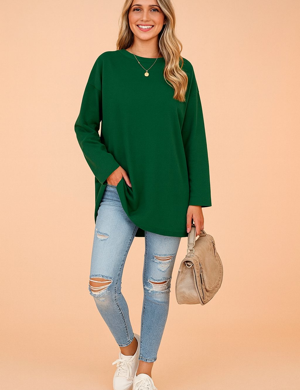Relaxed forest green long-sleeve tunic top paired with light blue distressed skinny jeans, styled with a beige handbag and white sneakers.