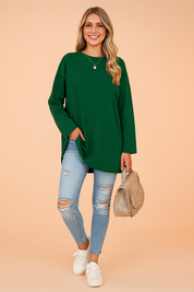 Relaxed forest green long-sleeve tunic top paired with light blue distressed skinny jeans, styled with a beige handbag and white sneakers.