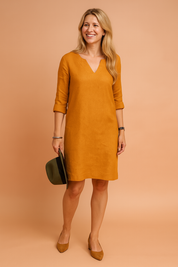 Minimalist knee-length shift dress with a notched neckline, 3/4 sleeves, and soft textured finish, featuring a clean straight cut and relaxed silhouette.