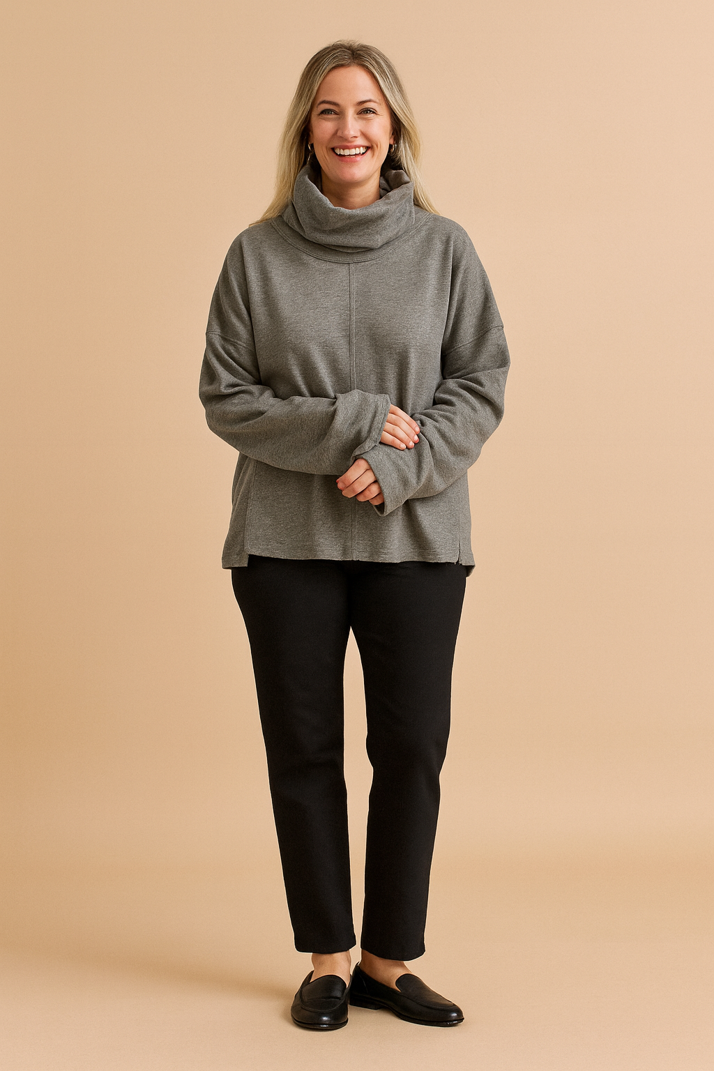 Oversized gray cowl-neck sweatshirt with dropped shoulders and front seam detail, styled with black straight-leg pants and black ankle boots.