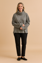 Oversized gray cowl-neck sweatshirt with dropped shoulders and front seam detail, styled with black straight-leg pants and black ankle boots.