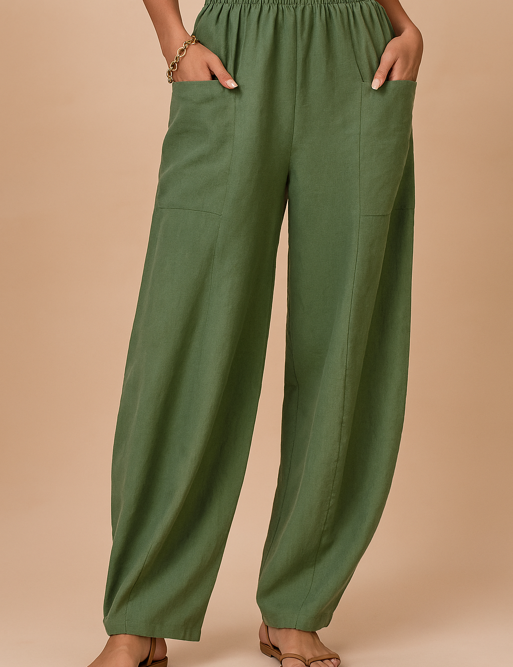 Wide-leg sage green linen pants with an elastic waistband and large front patch pockets, styled with flat tan sandals and a cropped beige top.